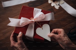 una persona che tiene una scatola regalo rossa con un cuore tagliato fuori