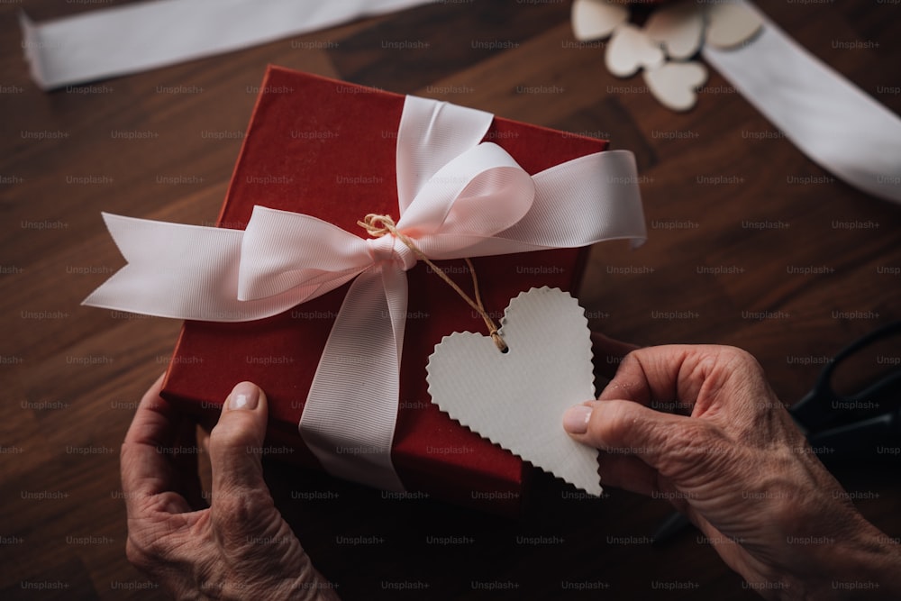 a person holding a red gift box with a heart cut out of it
