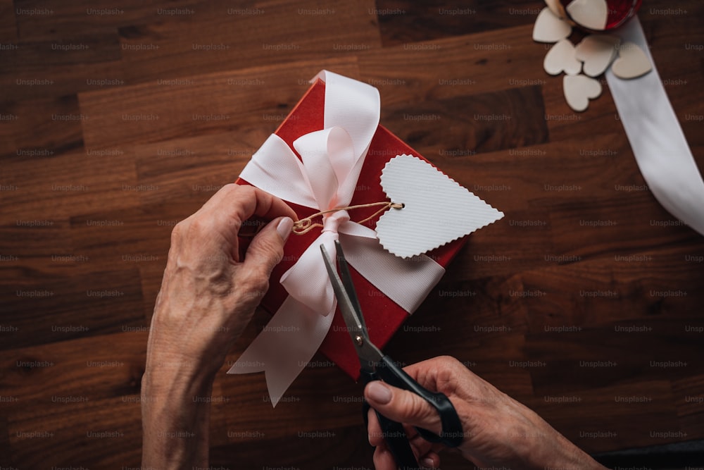a person cutting a gift with scissors on a table