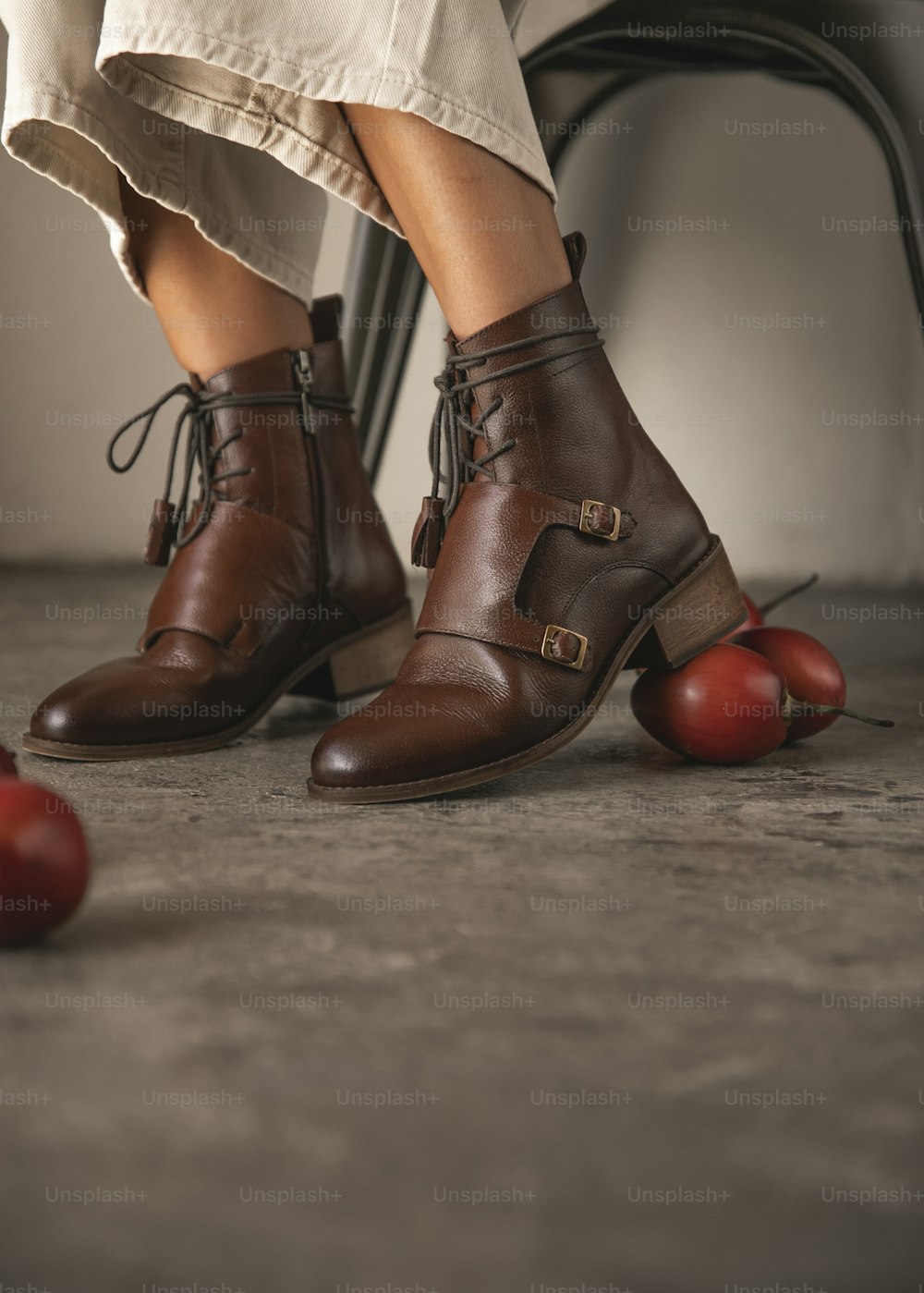 Die Beine einer Frau mit braunen Schuhen und Äpfeln auf dem Boden