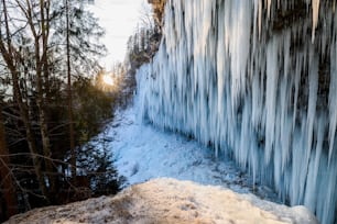 a frozen waterfall with trees and snow on the ground