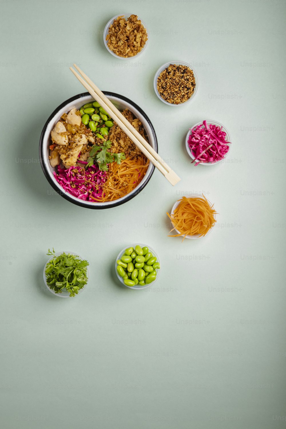 a bowl of food with chopsticks and bowls of vegetables