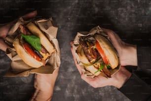 two people holding sandwiches in their hands
