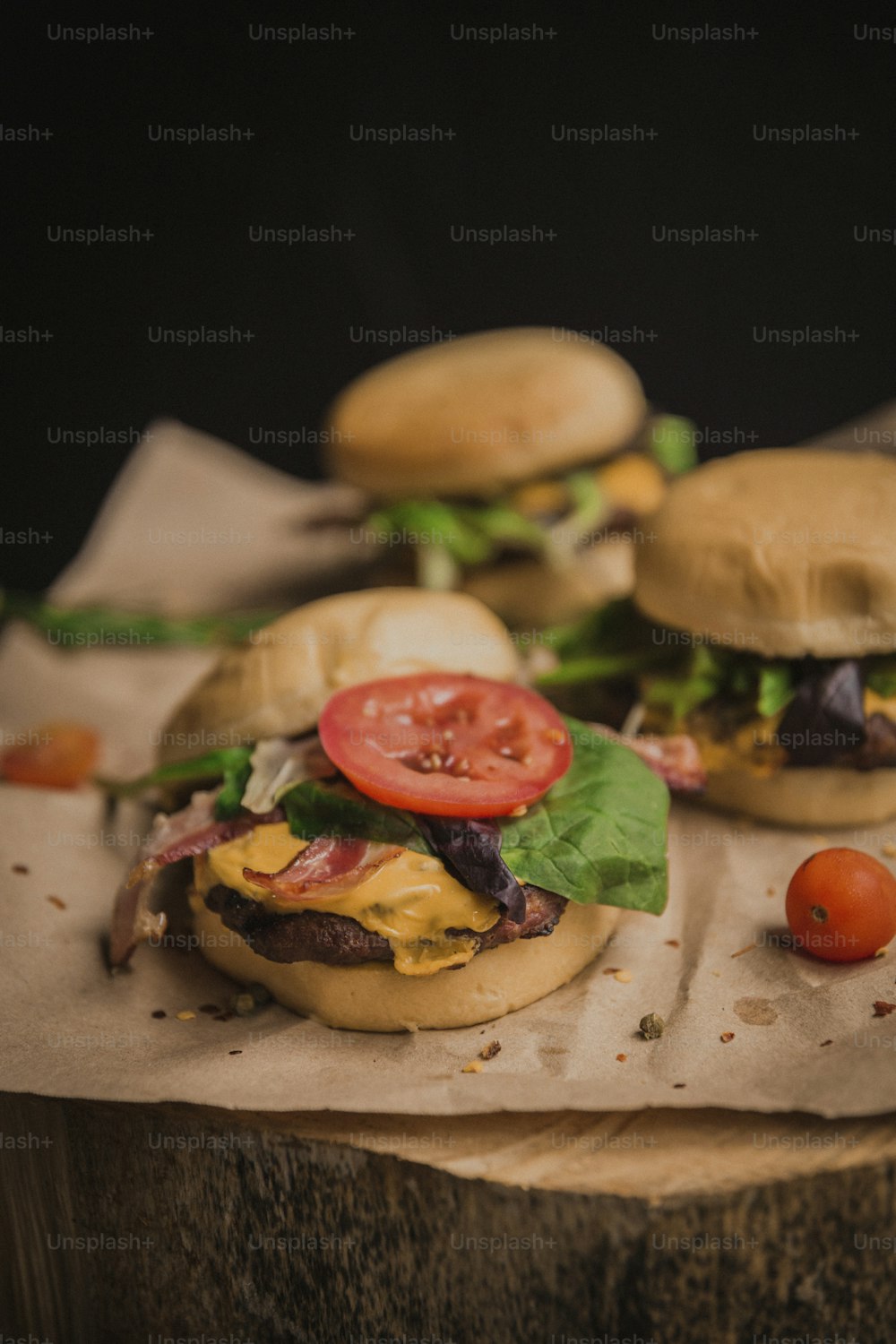 a table topped with three hamburgers covered in lettuce and tomatoes