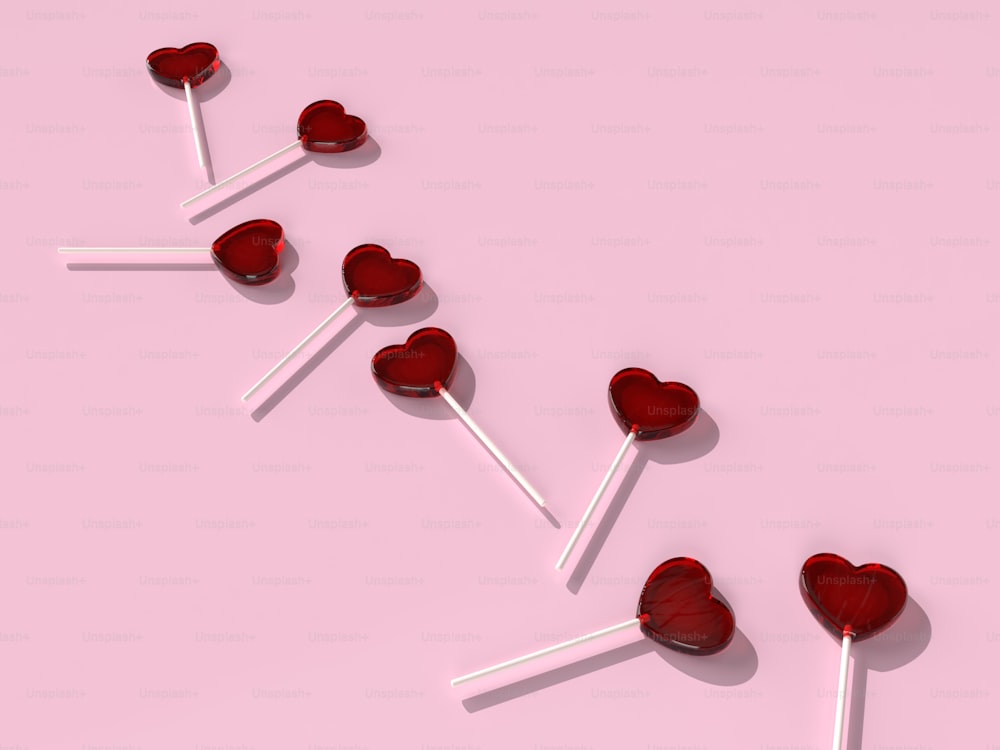 una fila di lecca-lecca a forma di cuore su uno sfondo rosa