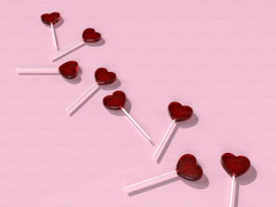 a row of heart shaped lollipops on a pink background