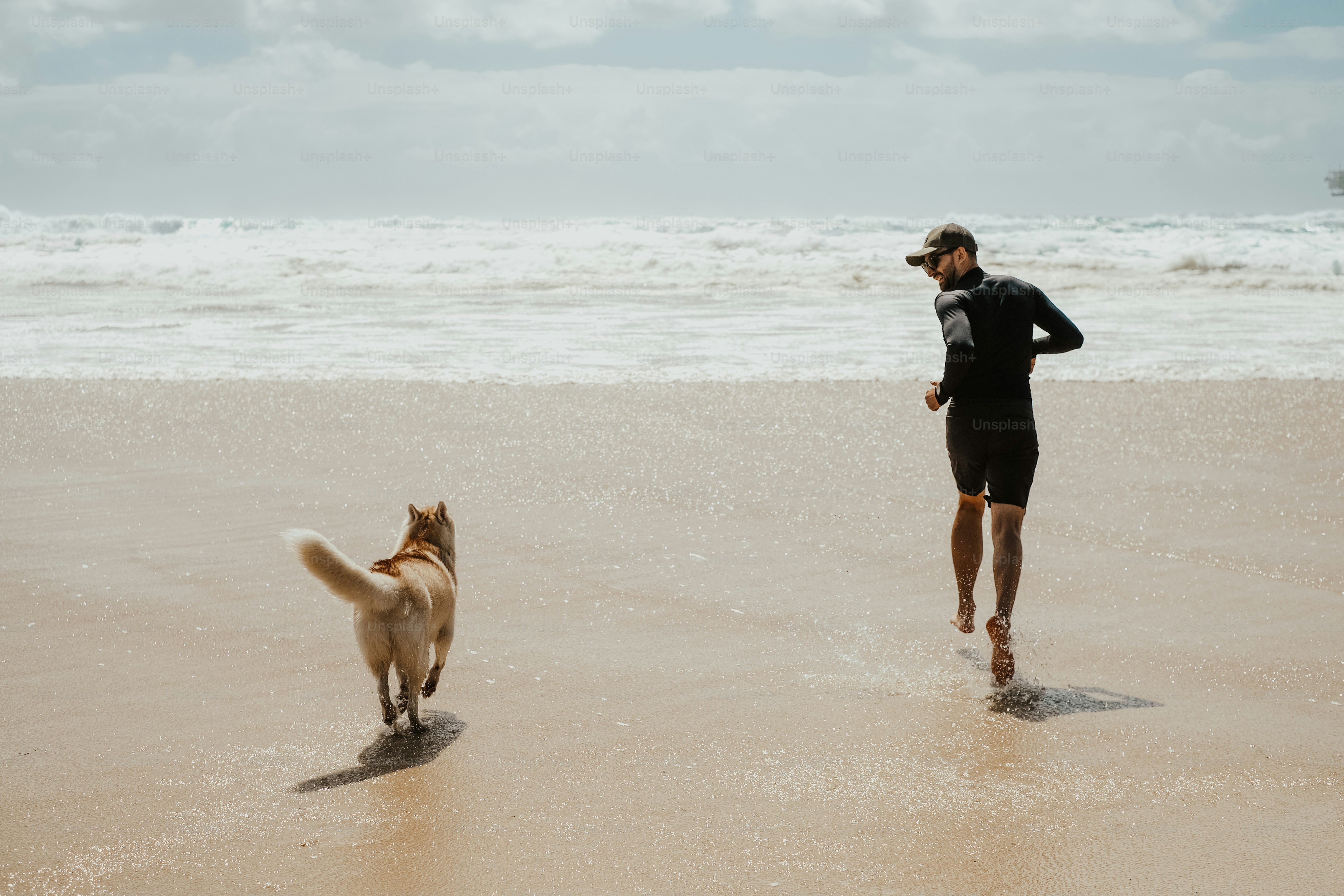 a man running on the beach with his dog