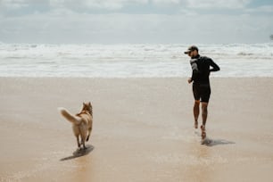 Un uomo che corre sulla spiaggia con il suo cane