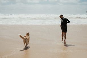 a man running on the beach with his dog