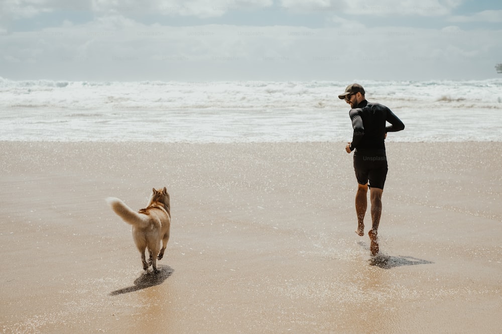 a man running on the beach with his dog
