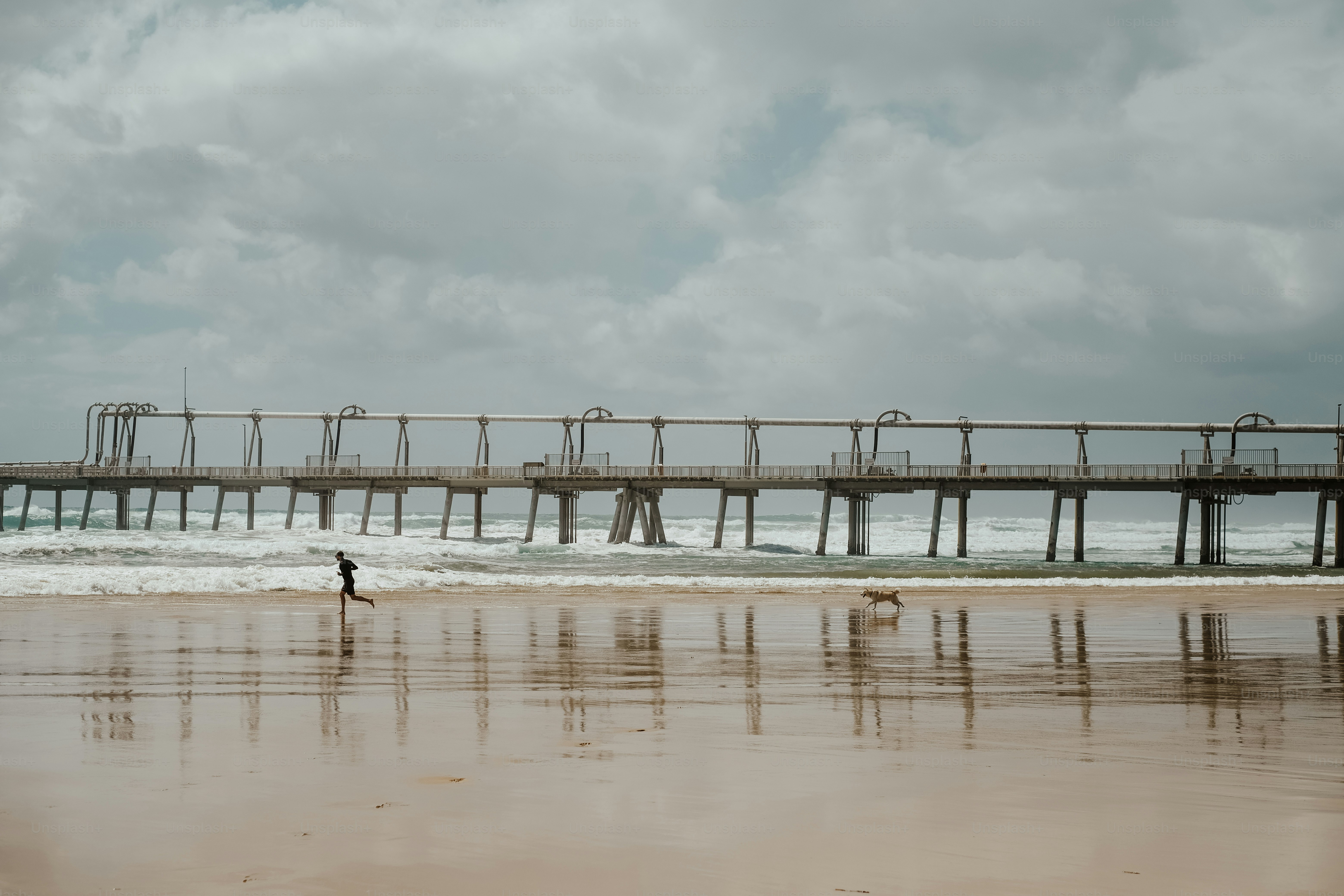 a person walking on a beach near a pier