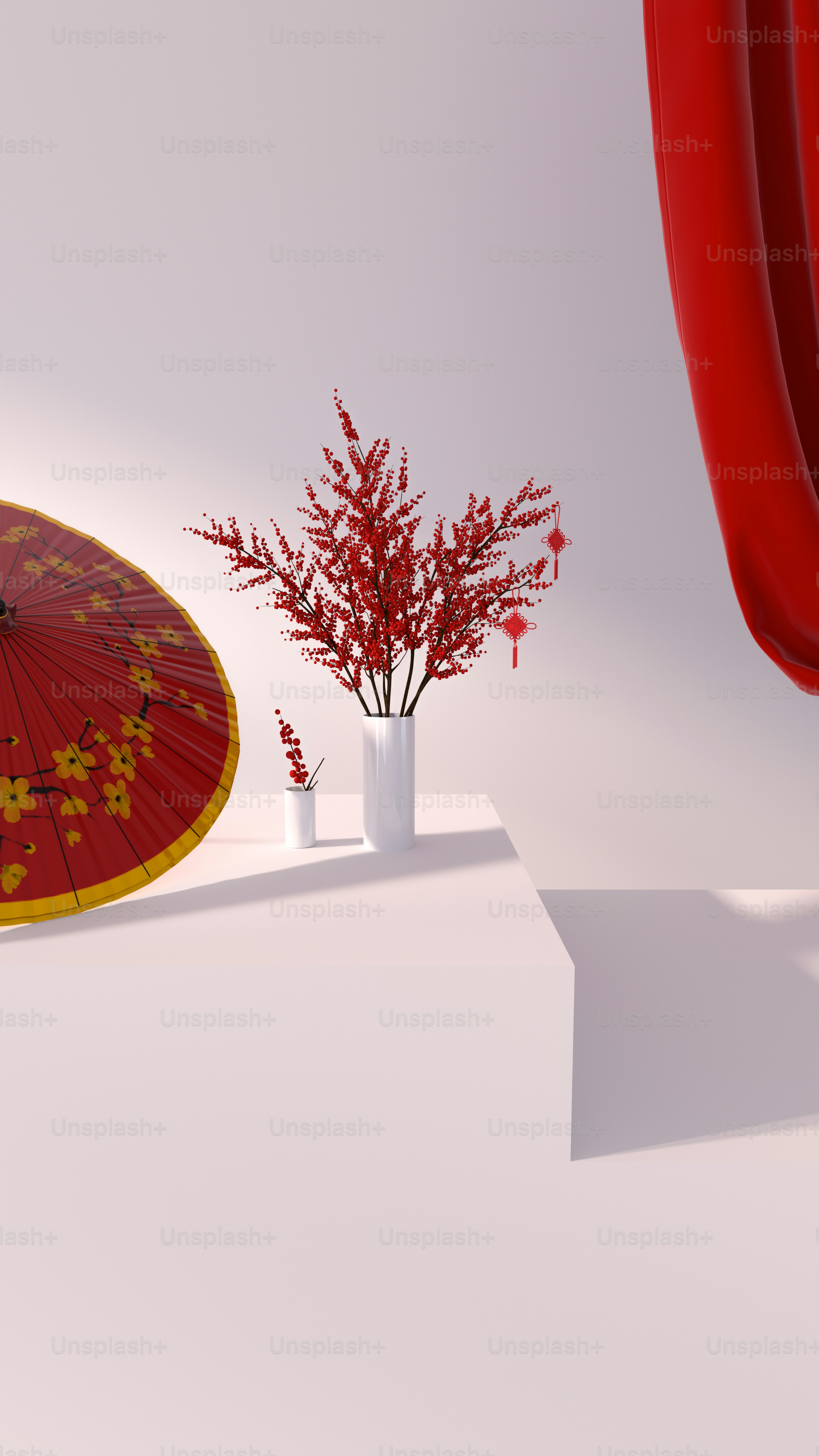 a red and yellow umbrella next to a white vase with red flowers