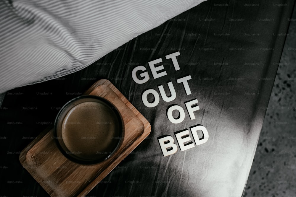 un lit avec un plateau en bois avec une tasse de café sur le dessus
