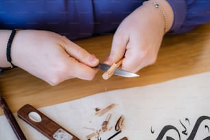 a woman is holding a knife over a piece of wood