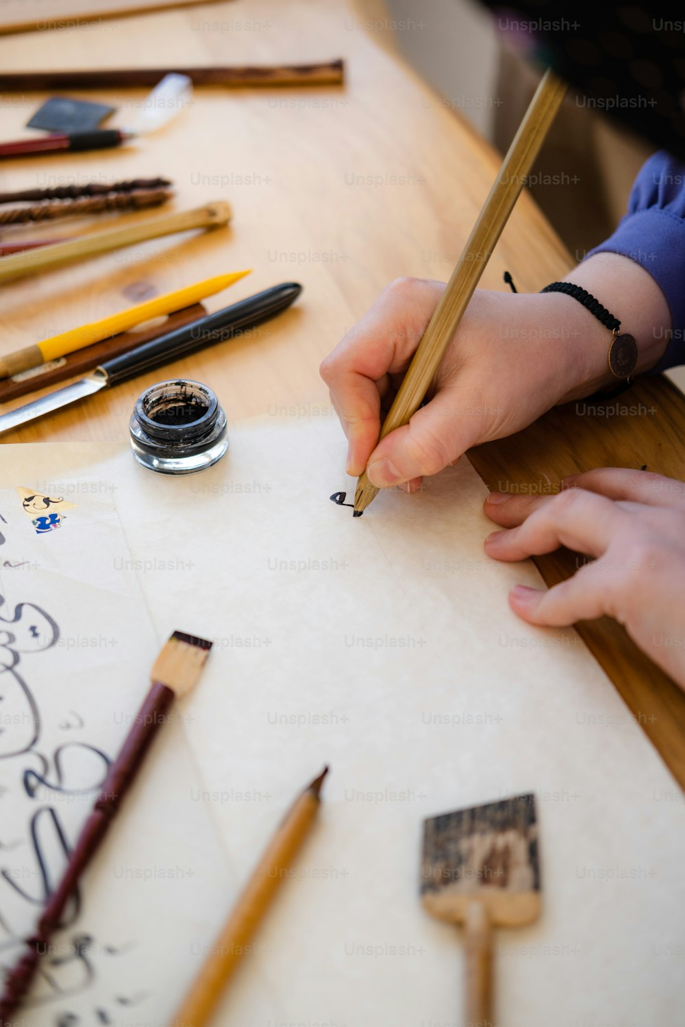 a person writing on a piece of paper with a pencil