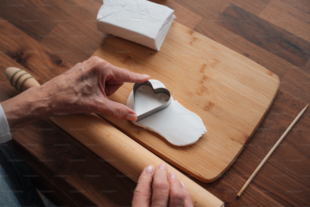 a person cutting a heart shaped cookie on a cutting board