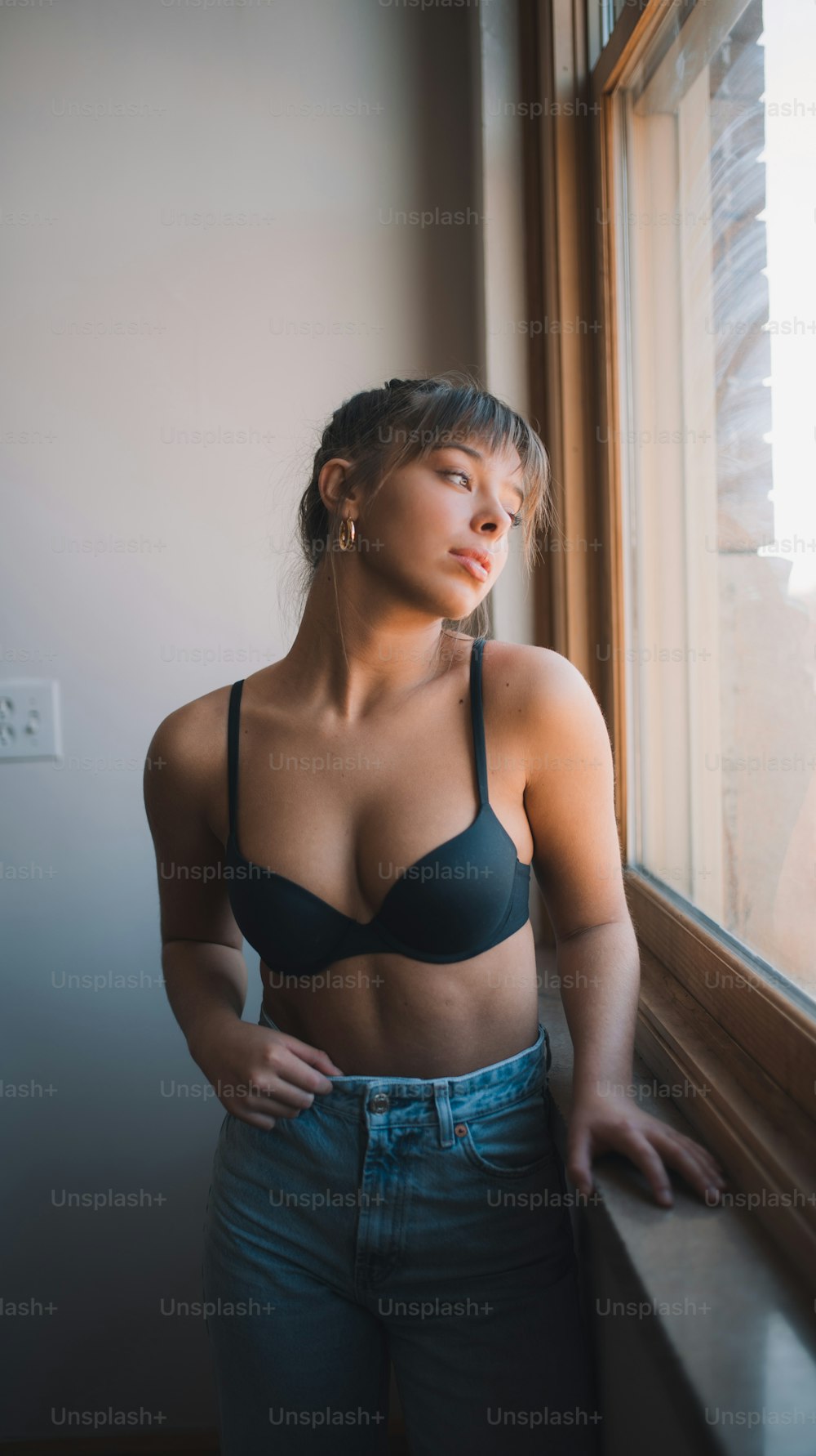 a woman in a bra looking out a window