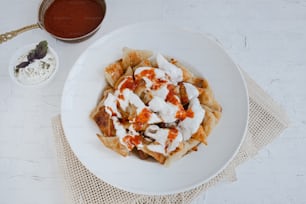a white plate topped with food next to a bowl of sauce