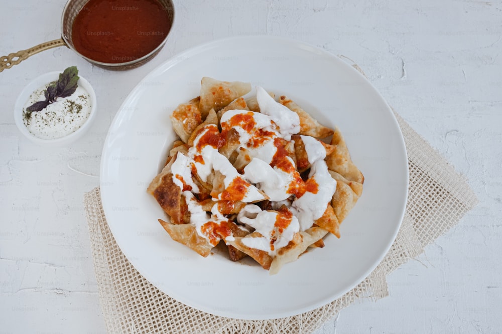 a white plate topped with food next to a bowl of sauce