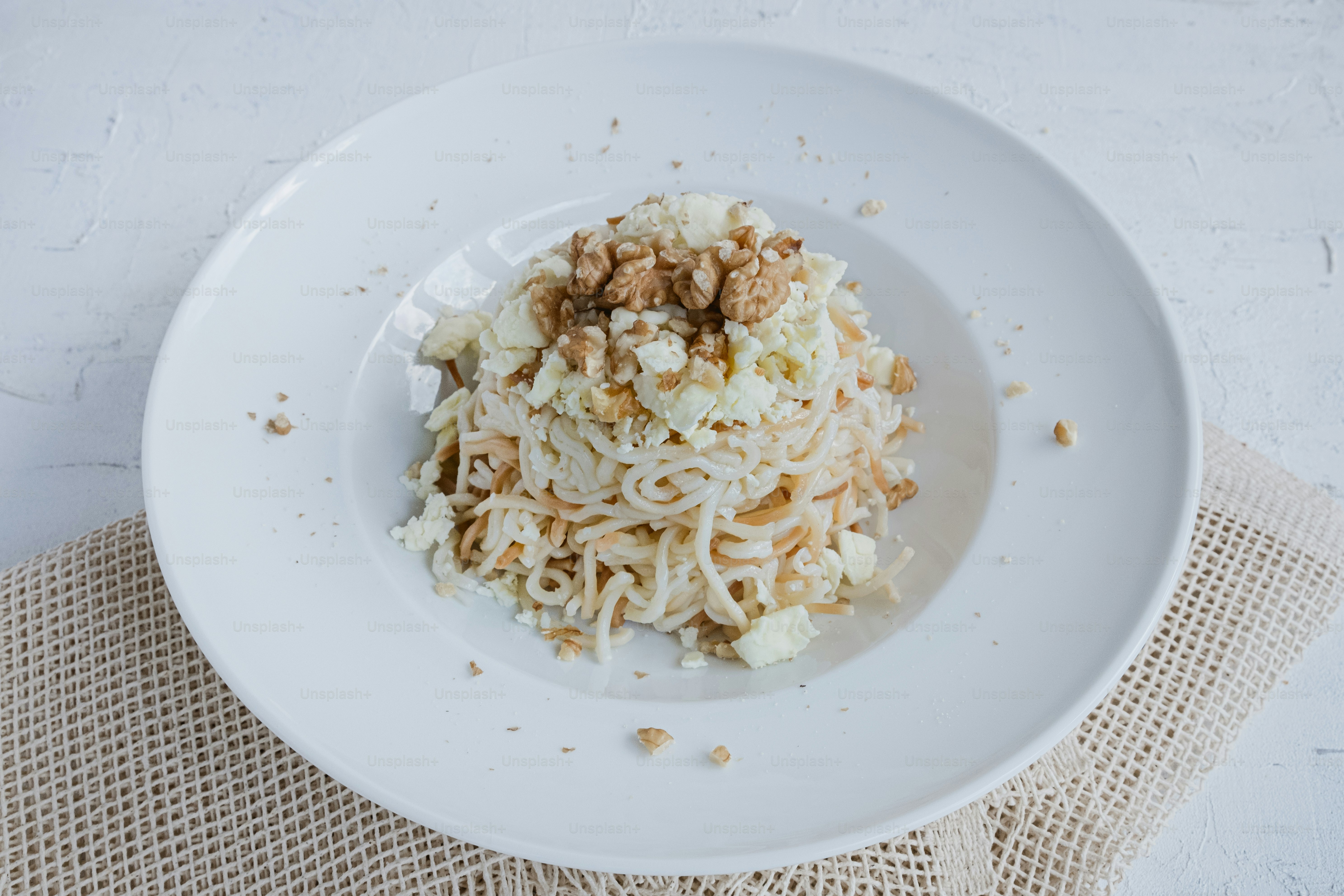 piring putih di atasnya dengan mie dan kacang-kacangan