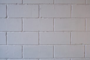 uma parede de tijolos brancos com um sinal de parada vermelho sobre ele