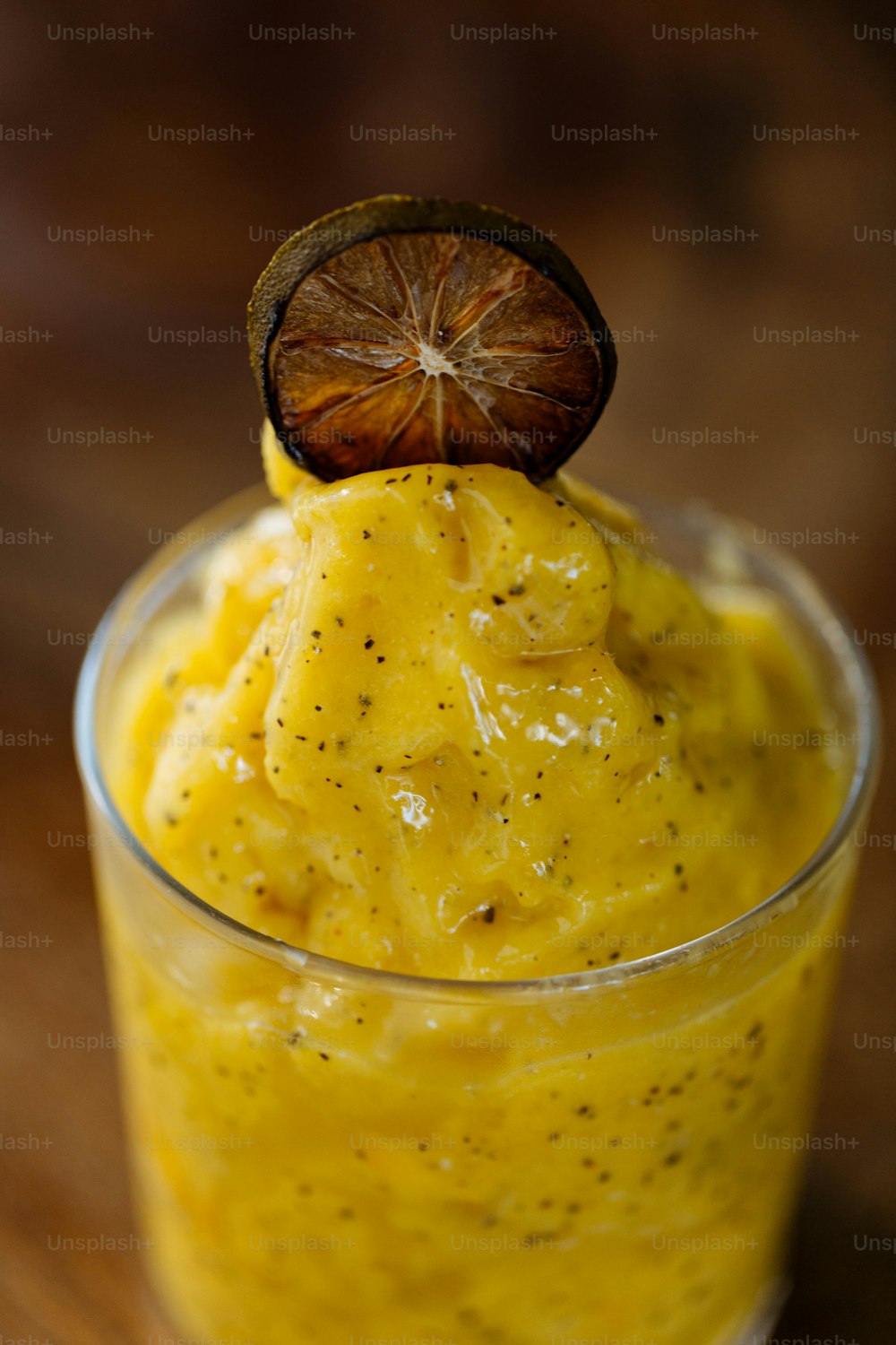 un verre rempli de liquide jaune et un fruit sur le dessus