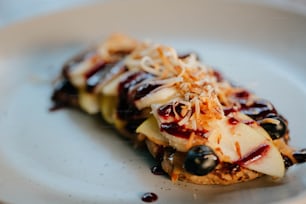 a white plate topped with a pastry covered in toppings