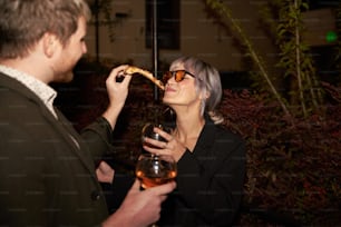 a man and a woman eating pizza and drinking wine