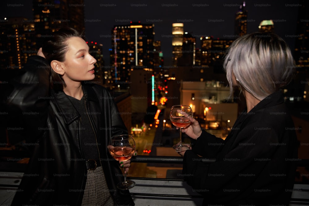 a couple of women standing next to each other holding wine glasses