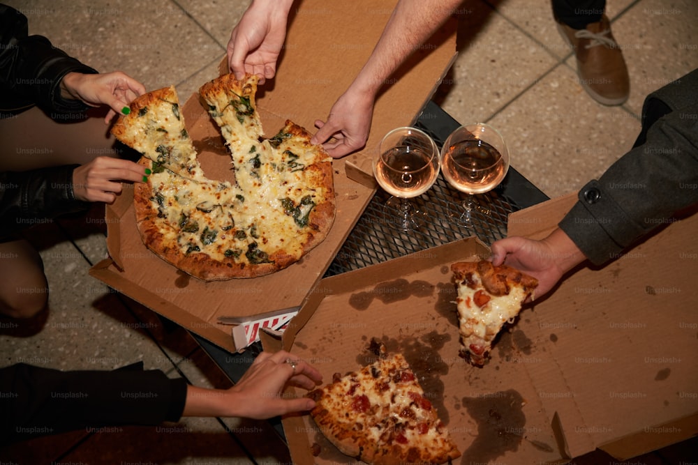 Un grupo de personas agarrando rebanadas de pizza