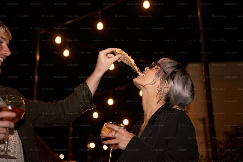 a man and a woman eating pizza and drinking wine