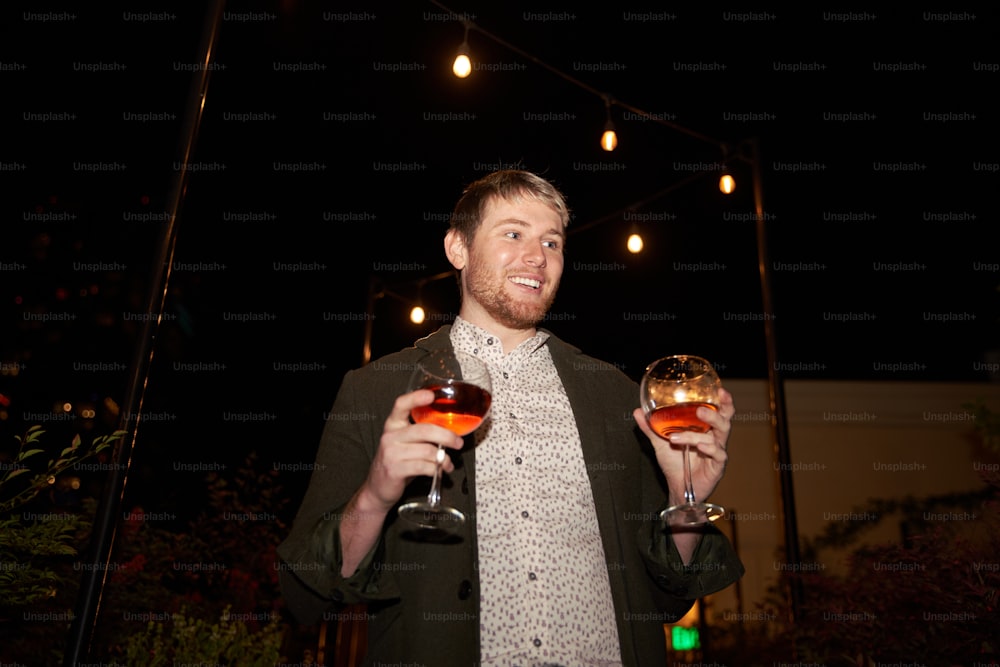 a man holding two wine glasses in his hands