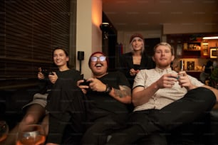 a group of people sitting on a couch holding remotes