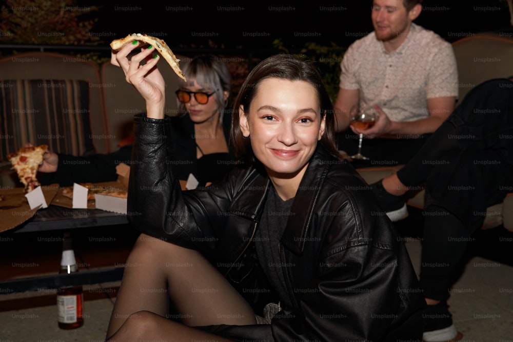 a woman holding up a piece of pizza