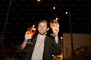 a man holding two wine glasses in his hands