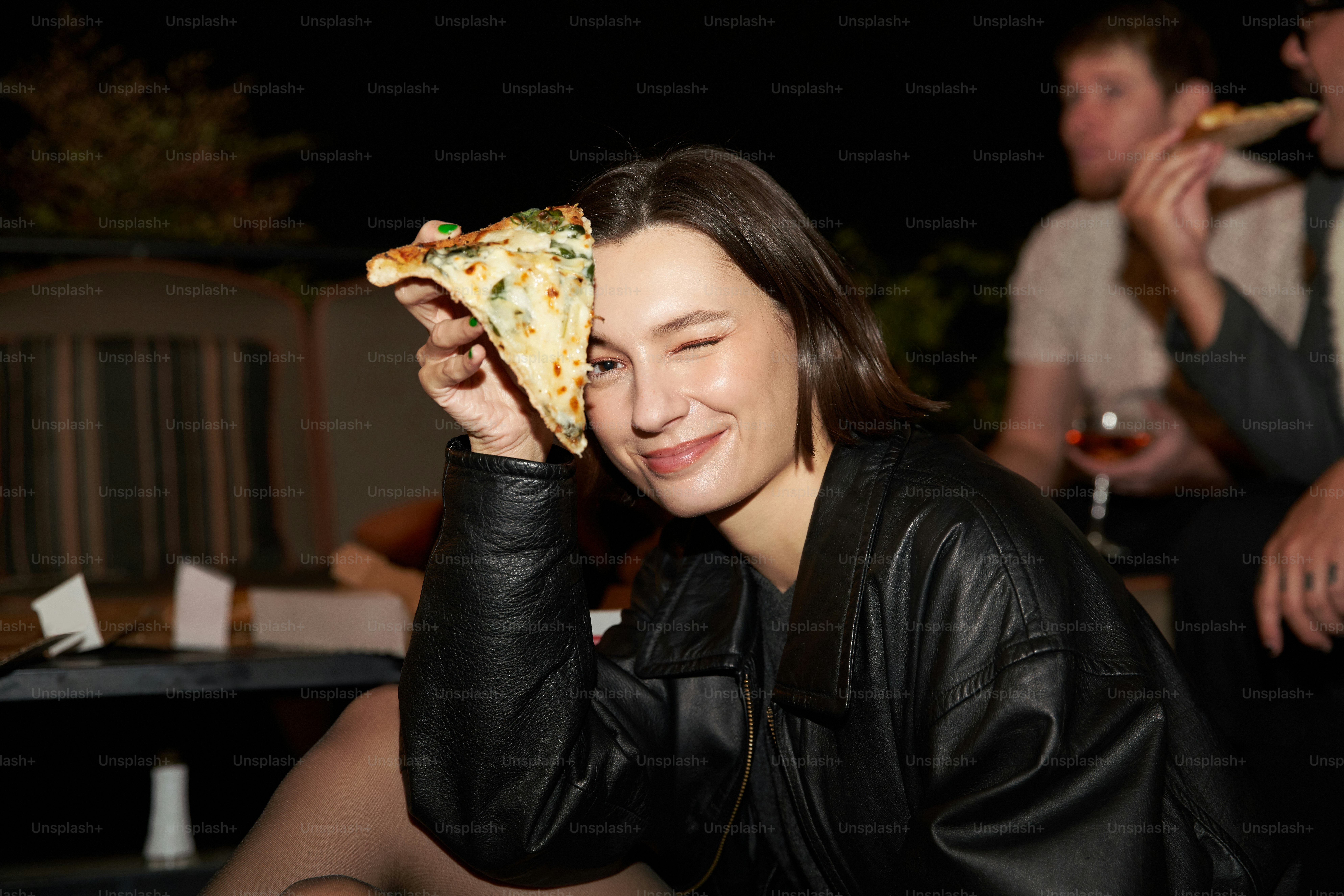a woman holding a slice of pizza up to her face