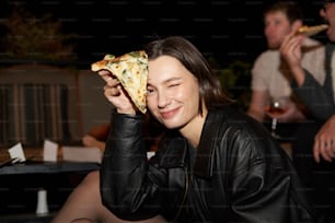 a woman holding a slice of pizza up to her face