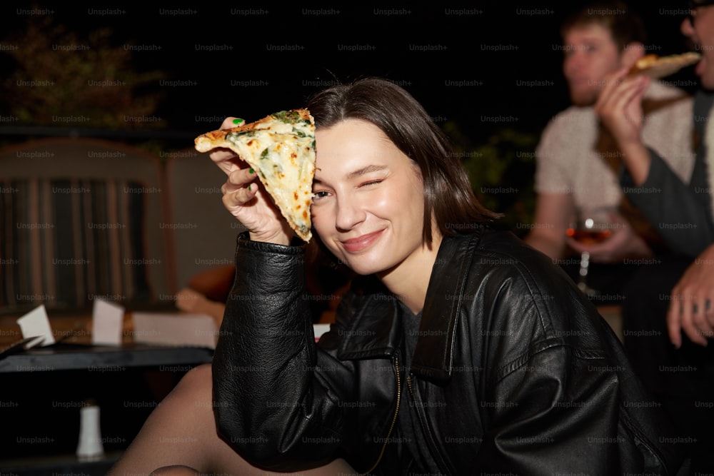 Una mujer sosteniendo una rebanada de pizza en su cara