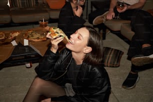 Una donna sta mangiando una fetta di pizza