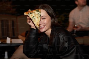 uma mulher segurando uma fatia de pizza até o rosto