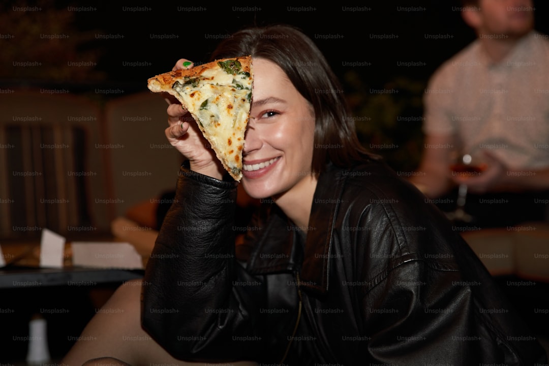 a woman holding a slice of pizza up to her face