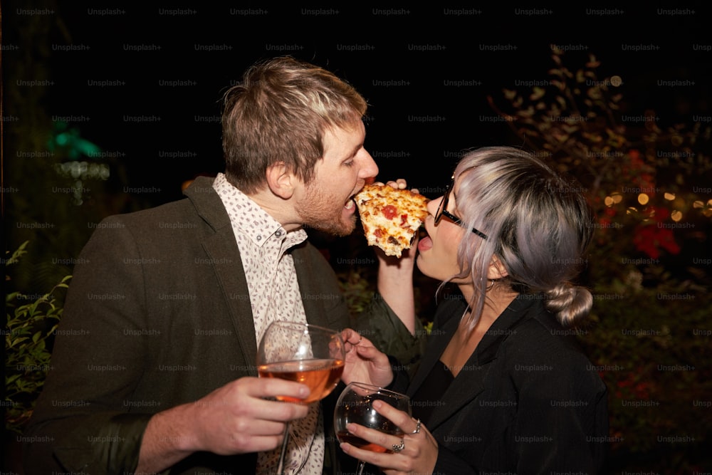 un hombre y una mujer comiendo pizza y bebiendo vino