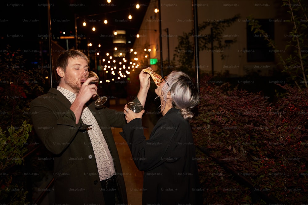 a man and a woman standing next to each other drinking wine