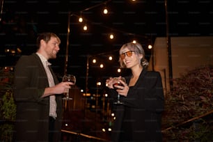 a man and a woman standing next to each other holding wine glasses