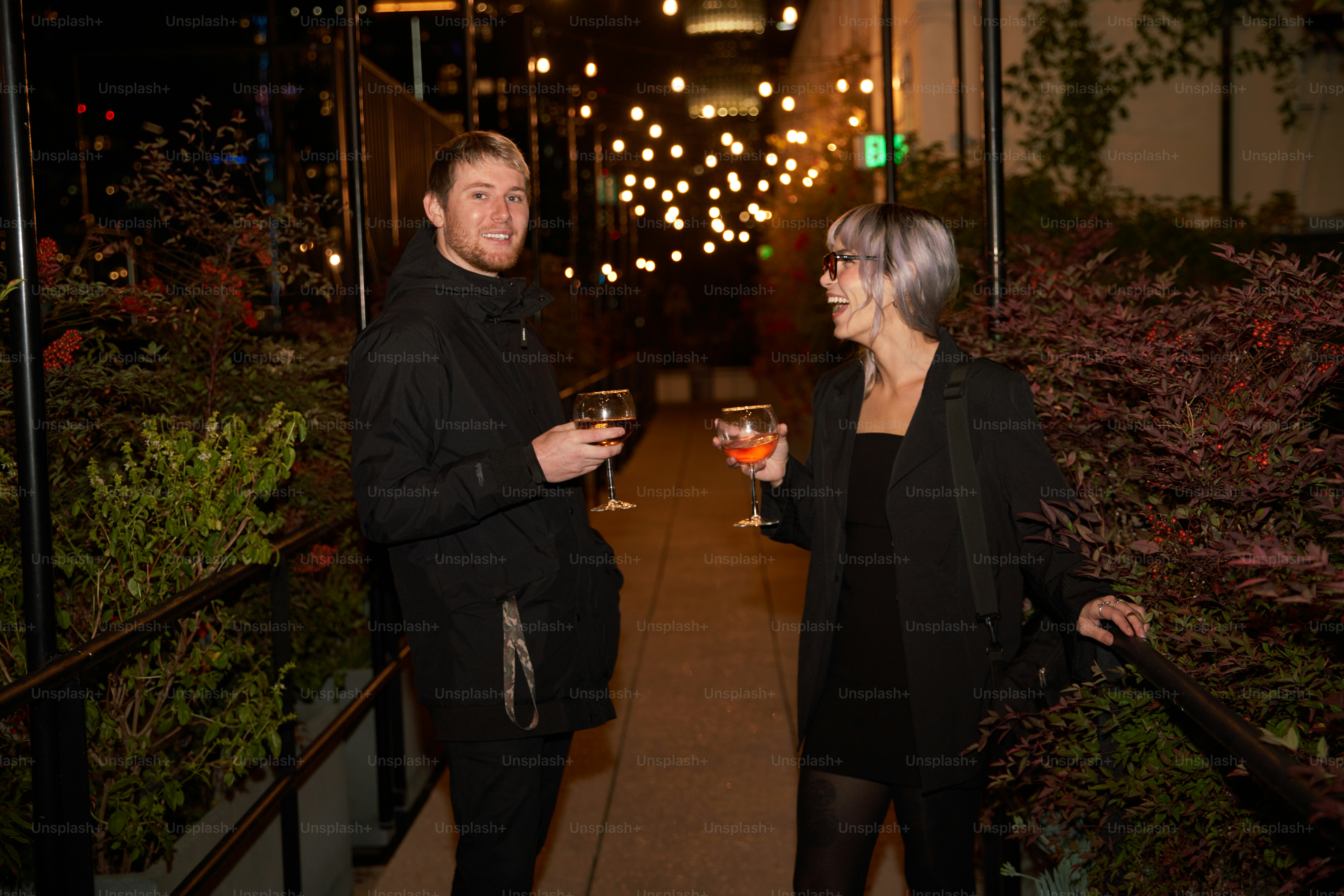 a man and a woman standing next to each other holding wine glasses