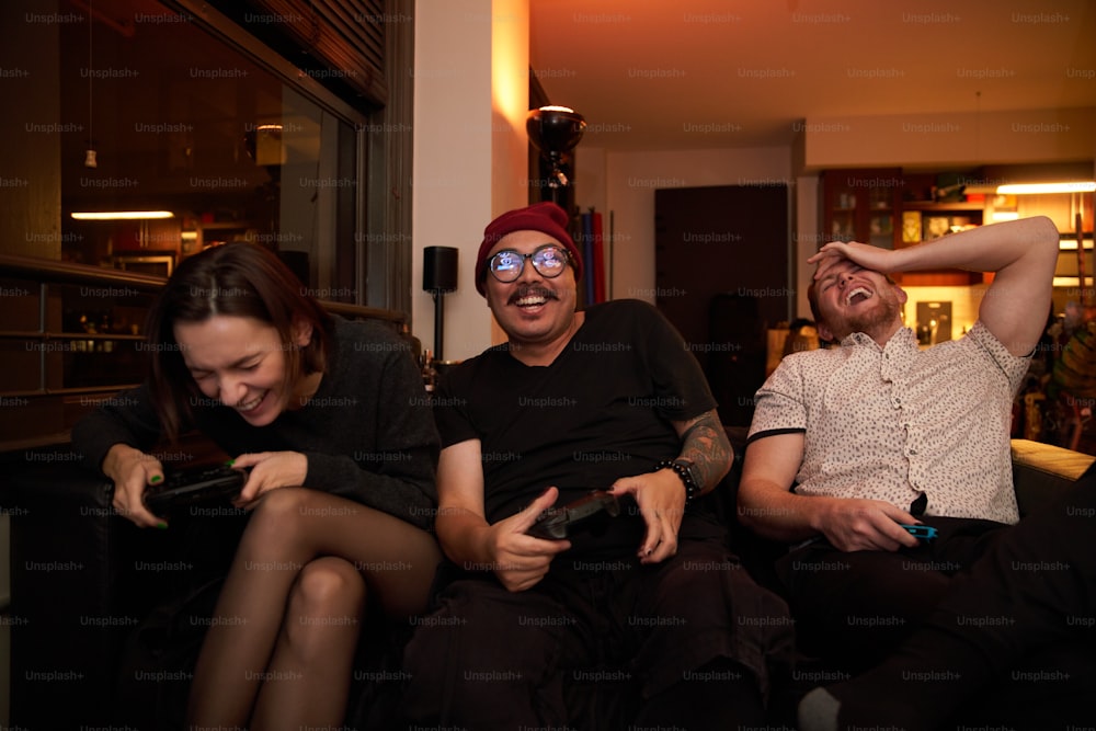 a group of people sitting on a couch with remotes
