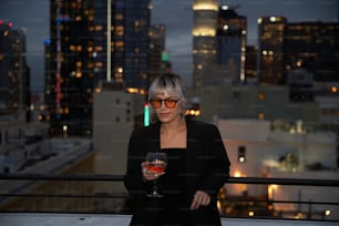 a woman holding a glass of wine in front of a city skyline