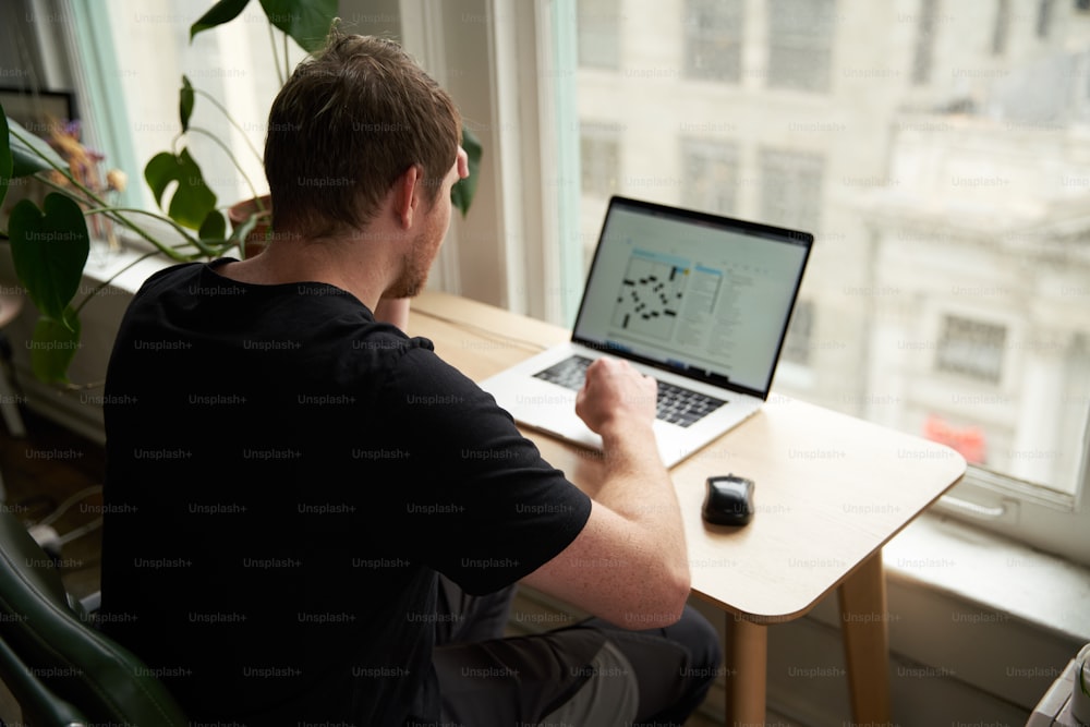 a man sitting at a desk using a laptop computer