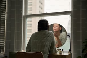 Una mujer mirándose en un espejo mientras se cepilla los dientes