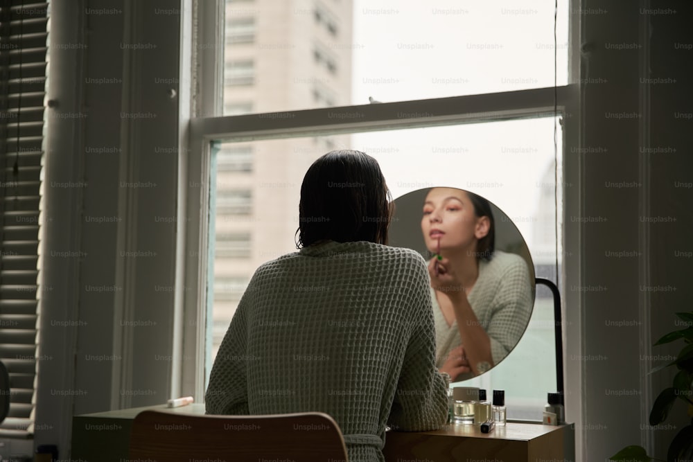 a woman looking in a mirror while brushing her teeth